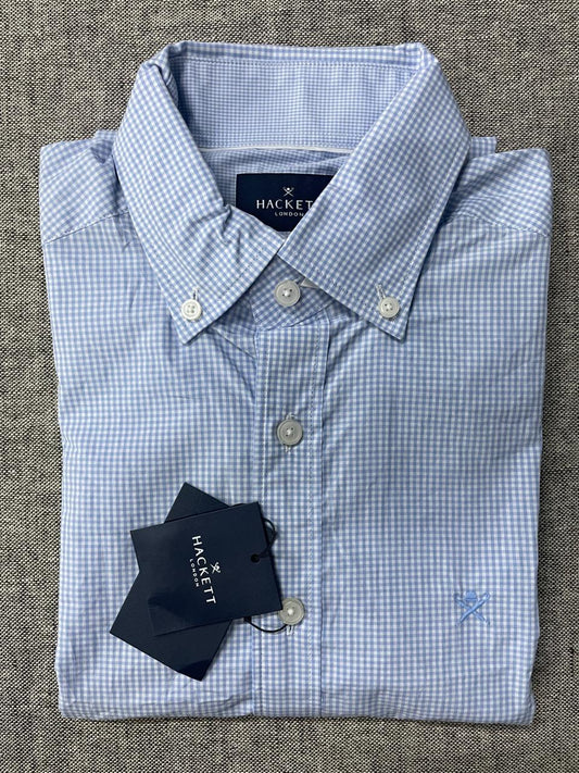 Folded blue checkered shirt with Hackett label on a textured surface