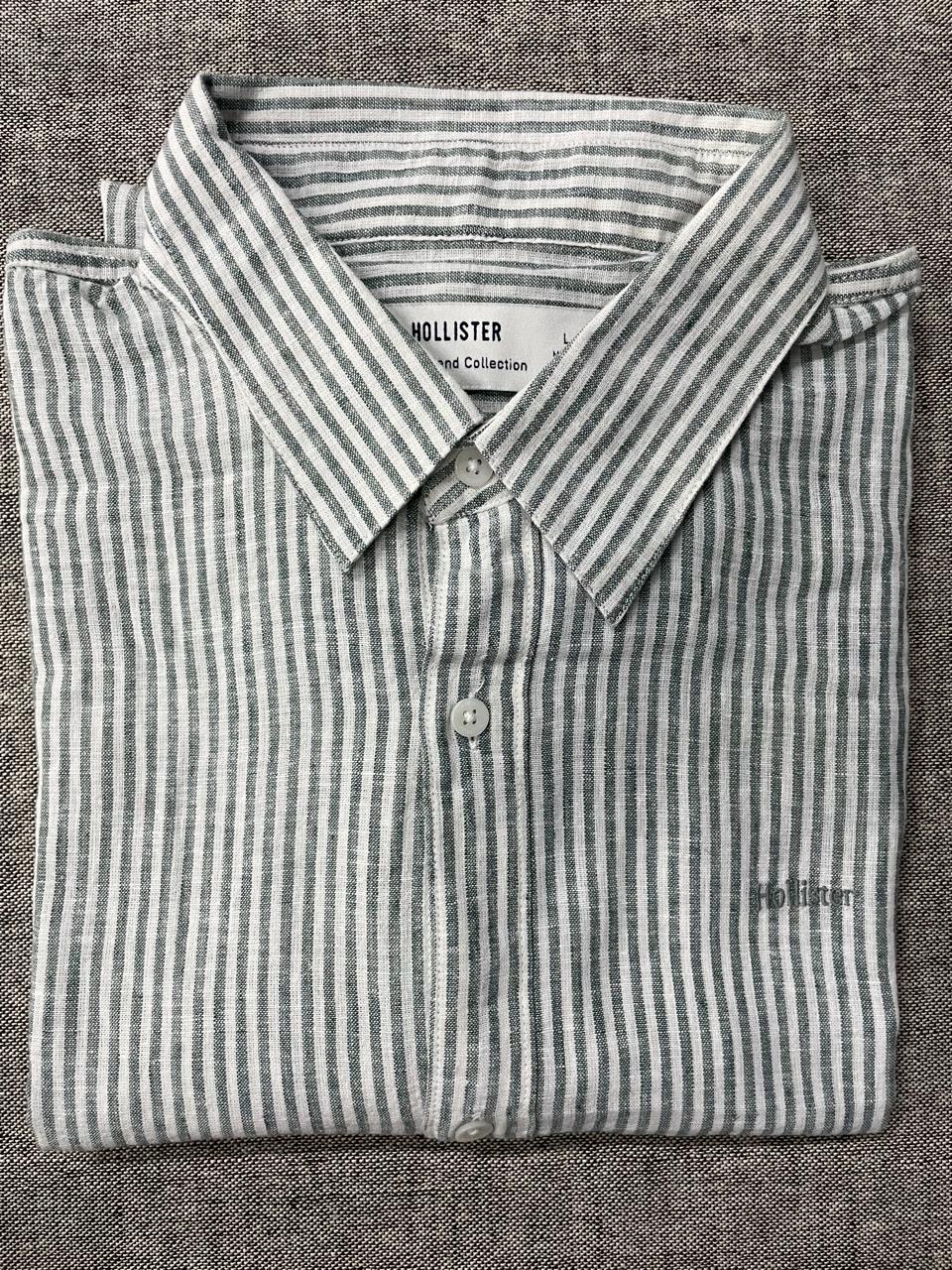 Folded Hollister striped shirt on a textured gray background